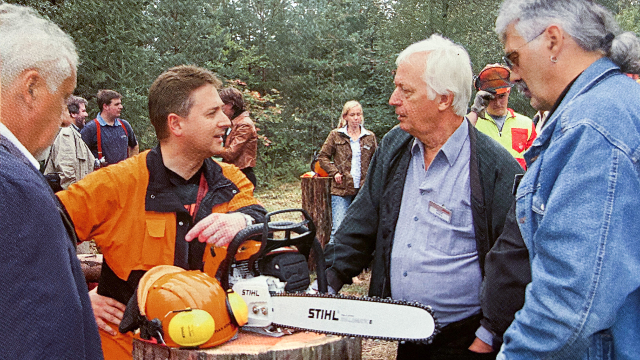 A group of men circling a STIHL chainsaw.