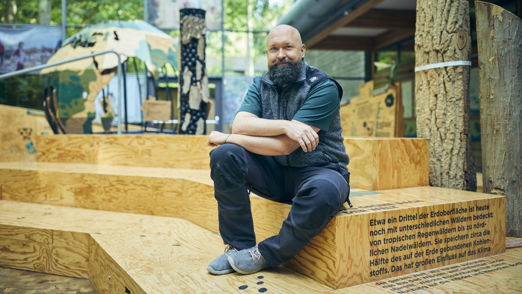 A man sitting in a bright room surrounded by wooden elements.