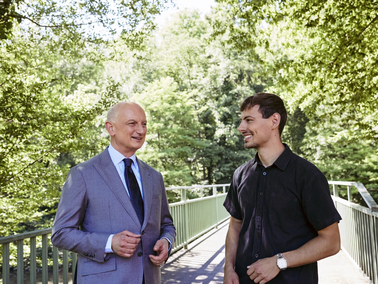 Dr. Nikolas Stihl and Tamino Soubawi stand on a bridge surrounded by trees.