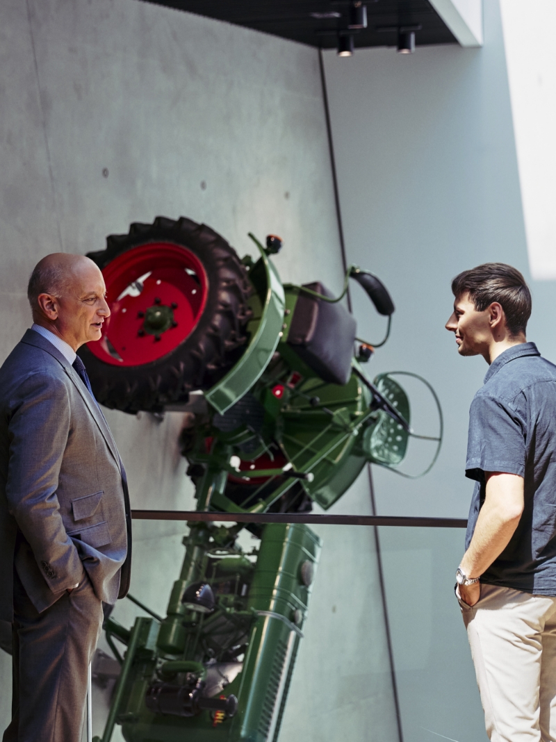Dr. Nikolas Stihl and Tamino Soubawi in conversation; a tractor hangs vertically on the wall behind them.