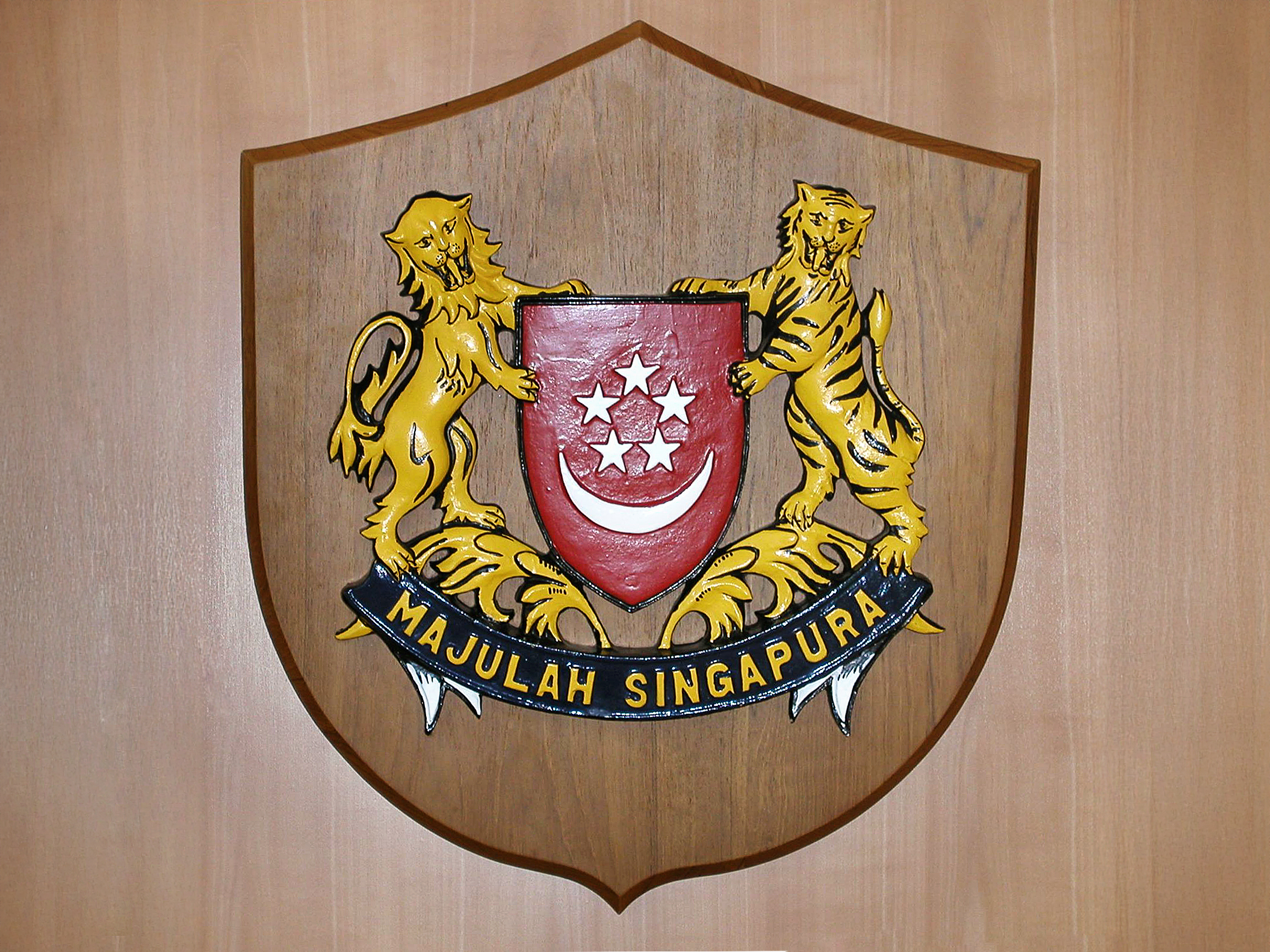 The emblem of the Republic of Singapore depicts a lion and a tiger flanking a red shield with a moon and five stars.