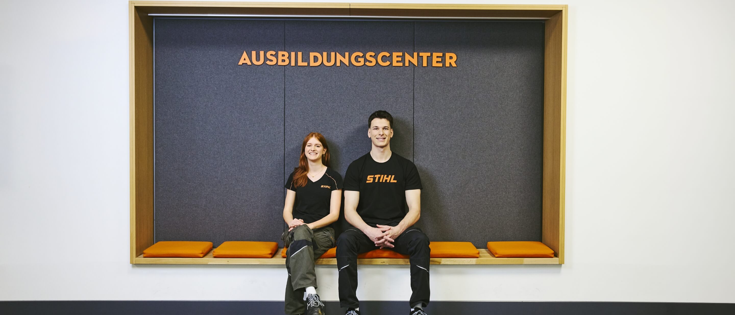 A young woman and a young man sit in a seating nook beneath the sign &ldquo;Training Center&rdquo;.