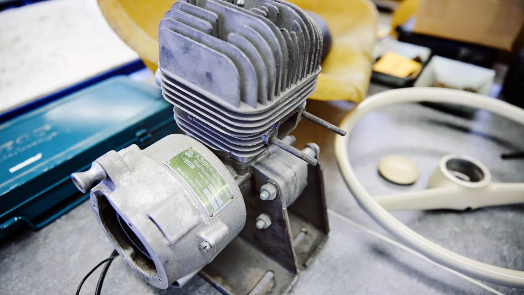 Close-up of the disassembled engine alongside the go-kart&rsquo;s steering wheel and seat.